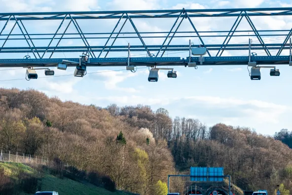 Close-up of Slovenia A2 motorway e-vinjeta enforcement gantry with multiple cameras and sensors mounted on truss beam with tunnel entrance and 100 km/h speed limit visible, April 2026