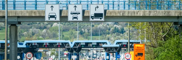 Obrežje Slovenia–Croatia border crossing with overhead lane signs for cars, buses and trucks, control booths and 40 km/h limit signs